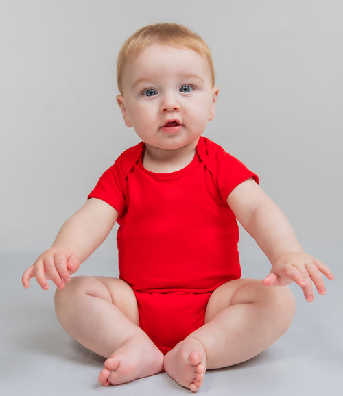 toddler wearing bright-red baby grown and blue trousers